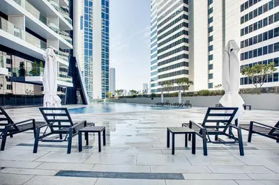 a group of chairs and tables in a courtyard with buildings at Stylish studio in Marquise Square Tower in Dubai