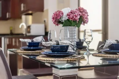 a table with plates and glasses and a vase of flowers at The Smart Concierge - Amwaj 4 in Dubai