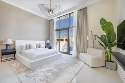 a white bedroom with a bed and a chair at Daniels Golf Course 5BR Villa with Private Pool in Dubai