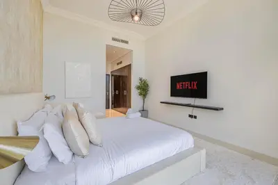 a white bedroom with a bed and a tv at Daniels Golf Course 5BR Villa with Private Pool in Dubai