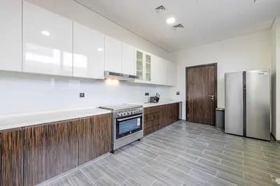 a kitchen with white cabinets and a stainless steel refrigerator at Daniels Golf Course 5BR Villa with Private Pool in Dubai