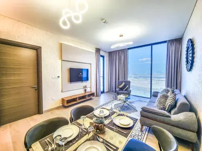 a living room with a table and chairs and a television at STAY BY LATINEM Luxury 1 BR Holiday Home OPA 1601 near Burj Khalifa in Dubai
