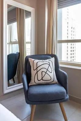 a blue chair with a pillow in a room with windows at GuestReady - Oliver Twist in Dubai
