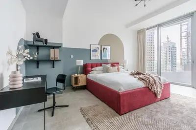 a white bedroom with a red bed and a desk at GuestReady - Modern Mirza with Marina View in Dubai