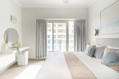 a white bedroom with a large bed and a large window at Frank Porter - Opal Tower in Dubai