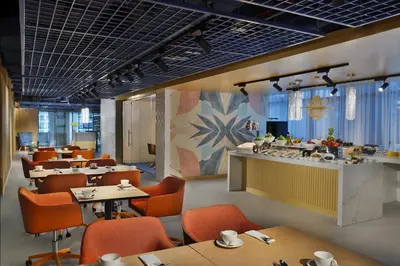 a restaurant with orange chairs and tables and a counter at NH Collection Dubai The Palm in Dubai