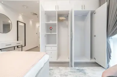 a white bedroom with a bed and a mirror at Boutique Luxury Living near Palm Jumeirah in Dubai