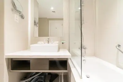 a white bathroom with a sink and a shower at Vacay Lettings - Waterfront Studio with great Dubai Canal view in Dubai