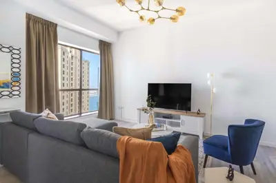 a living room with a gray couch and a large window at GuestReady - Lux Aeterna in JBR in Dubai