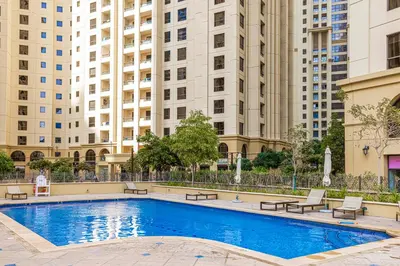a swimming pool with benches and buildings in the background at Spacious 2BD in Amwaj JBR near the beach in Dubai