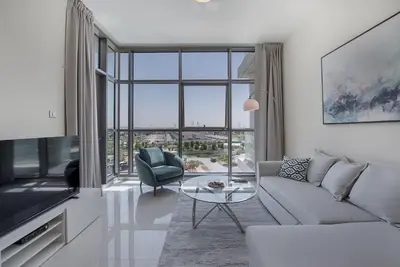 a living room with a couch and a table and a tv at Bright and spacious apartment in DAMAC HILLS in Dubai