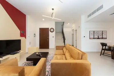 a living room with a couch and a tv at Stunning 4 bedroom townhouse in Townsquare in Dubai