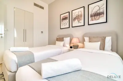 two white beds in a room with two chairs at Serene 2BR at The Nook Wasl Gate Jebel Ali by Deluxe Holiday Homes in Dubai