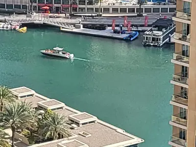 a boat in the water in a river with buildings at USMANS 5 BEDROOM APARTMENT at JBR WALK RIMAL ON THE BEACH 2750 SFT HUGE Direct Beach Access Fully Serviced JBR in Dubai