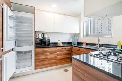 a kitchen with wooden cabinets and a white refrigerator at Modern 1BR in Dubai Marina Near Metro & Beach in Dubai