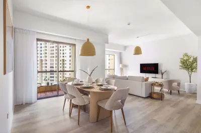 a white living room with a table and chairs at GuestReady - Sea la Vie - Lux in JBR in Dubai
