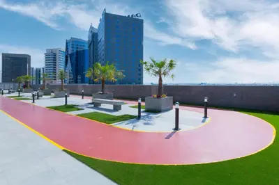 a park with palm trees and benches in a city at Spacious Studio I Close to Dubai Canal in Dubai