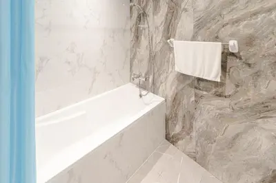 a bathroom with a white bath tub and a stone wall at Spacious Studio I Close to Dubai Canal in Dubai