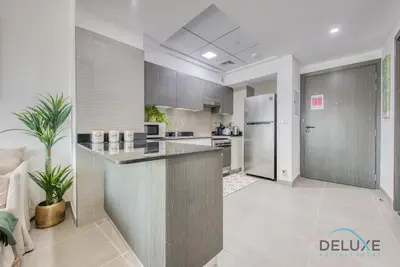 a large kitchen with a counter and a refrigerator at Vibrant 1BR in Bella Rose Al Barsha South by Deluxe Holiday Homes in Dubai
