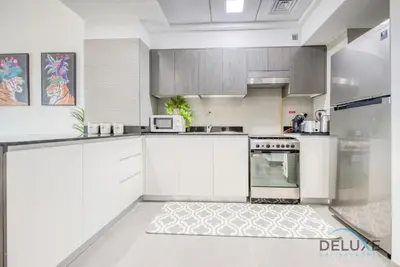 a kitchen with white cabinets and a stove at Vibrant 1BR in Bella Rose Al Barsha South by Deluxe Holiday Homes in Dubai