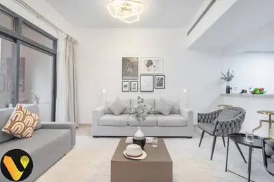 a living room with a couch and a table at Vogue The Greens Al Sidir near Mall of The Emirates, Three Bedroom Apartment with Balcony and full access to all amenities in Dubai