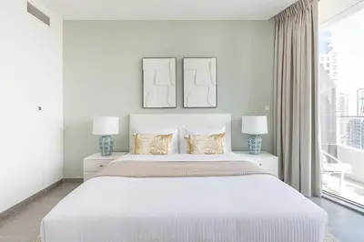 a white bedroom with a large bed with two lamps at Frank Porter - Stella Maris in Dubai