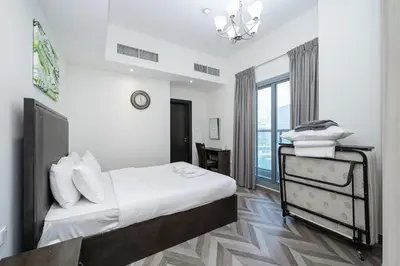 a white bedroom with a bed and a window at Stylish 4BR with Jacuzzi, Sauna & Prime Amenities in Dubai