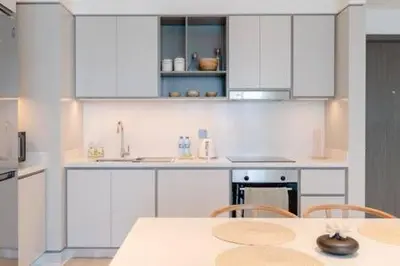 a kitchen with white cabinets and a table with chairs at Private Beachfront 1 Bed With 180 view of Marina Skyline in Dubai