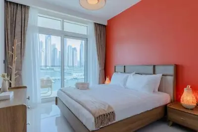 a bedroom with a large bed with a red wall at Private Beachfront 1 Bed With 180 view of Marina Skyline in Dubai
