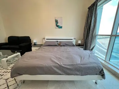a bedroom with a bed and a chair and a window at Studio - Steps from Downtown in Dubai