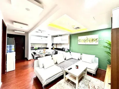 a living room with white furniture and a green wall at Cozy Apartment In Laya Residence JVC in Dubai