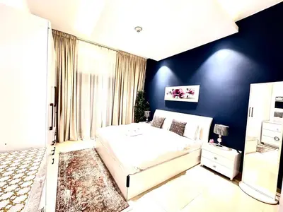 a bedroom with a white bed and a blue wall at Cozy Apartment In Laya Residence JVC in Dubai