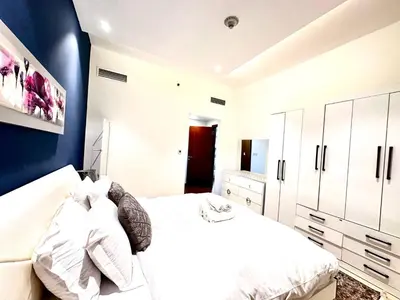 a bedroom with a white bed and a blue wall at Cozy Apartment In Laya Residence JVC in Dubai