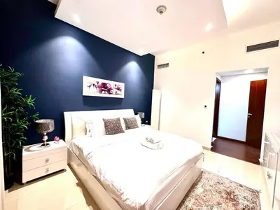 a bedroom with a white bed and a blue wall at Cozy Apartment In Laya Residence JVC in Dubai