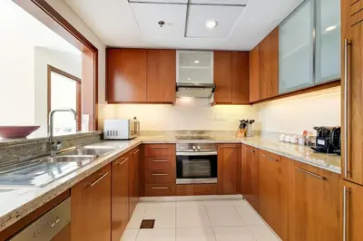 a kitchen with wooden cabinets and stainless steel appliances at Standpoint A, Downtown - Contemporary One Bedroom in Dubai