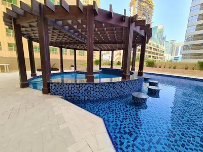 a swimming pool with a wooden gazebo in a building at Holiday Home near beach & metro in Dubai
