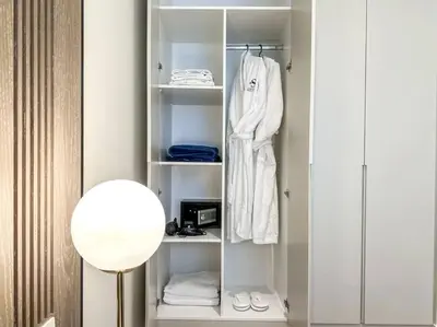 a white closet with a white robe and a lamp at Fantastic flat in TiaraResidence in Dubai