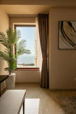 a living room with a window and a plant at Happy ACADEMIA JBR in Dubai