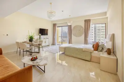 a living room with a bed and a dining room at Happy ACADEMIA JBR in Dubai