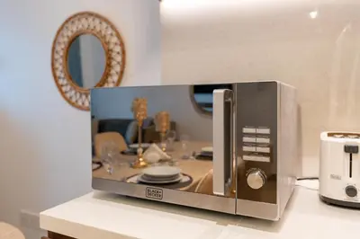 a microwave sitting on top of a counter at Stylish 1BR Apartment in La Mer Dubai with Balcony and Partial Marina Views in Dubai