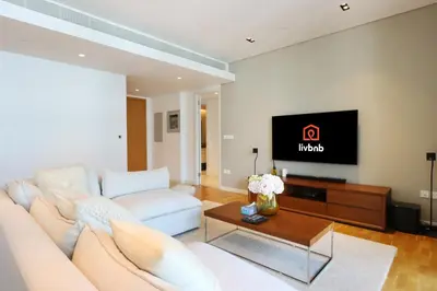 a living room with a white couch and a tv at High-End 1BR Bluewaters Luxury Near Ain Dubai in Dubai