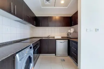 a kitchen with wooden cabinets and a washer and dryer at Bay Central, Dubai Marina - Peaceful One Bedroom in Dubai