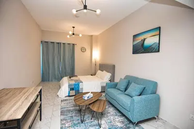 a living room with a blue couch and a bed at Exceptional Furnished Studio in Dubai