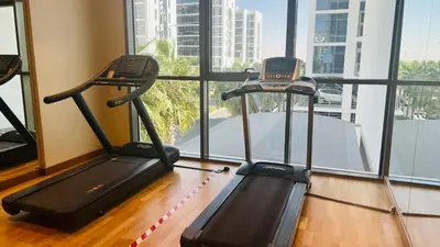 two treadmill machines in a room with a window at Newly Furnished bright and cozy studio apartment - Damac Hills in Dubai