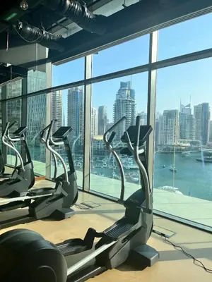 a gym with cardio machines and a view of the city at Luxurious 3BR Maid room 33rd Floor Marina Gate in Dubai
