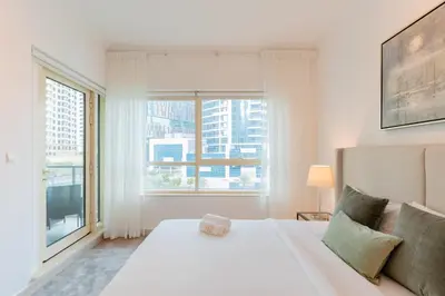 a bedroom with a white bed and a large window at Stylish Waterfront 2 Bed in Dubai Marina in Dubai