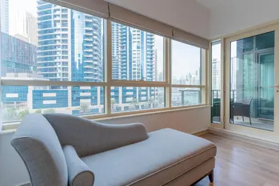 a living room with a chair and large windows at Stylish Waterfront 2 Bed in Dubai Marina in Dubai