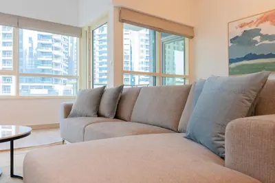 a couch in a living room with windows at Stylish Waterfront 2 Bed in Dubai Marina in Dubai
