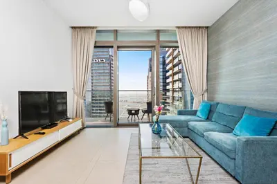 a living room with a blue couch and a tv at StoneTree - Marina Gate 2 BR - Partial Sea View in Dubai
