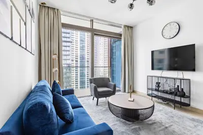 a living room with a blue couch and a tv at StoneTree - Marina Gate 2 BR - Prime location in Dubai